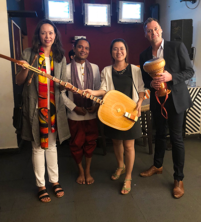 Mr. Raymond Hyma, far right, and Ms. Suyheang Kry, second from right, are seen standing with traditional Cambodian musical instruments (courtesy of Mr. Hyma and Ms. Kry).