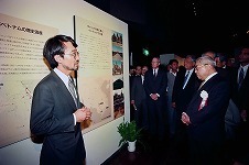 20周年記念事業「海のシルクロード――チャンパ王国の遺跡と文化展」（1995年）のオープニングで来場者を前に説明する重枝豊氏（日本大学理工学部建築学科研究員）。右端は豊田英二会長